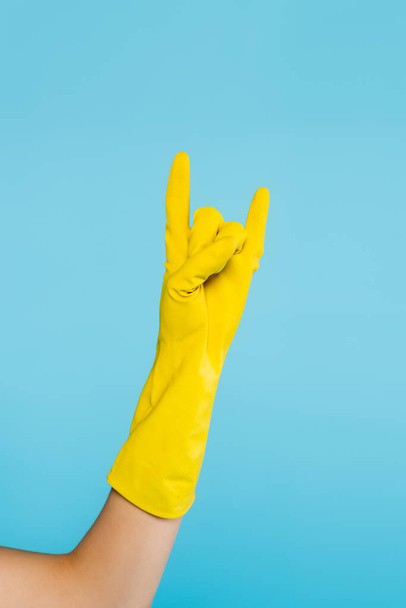 Kırpılmış sarı lastik eldivenli kadın mavi üzerinde kaya işareti gösteriyor. - Fotoğraf, Görsel