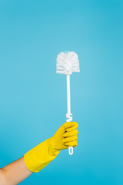 vue partielle de la femme au foyer en gant de caoutchouc jaune tenant la brosse de toilette isolée sur bleu - Photo, image