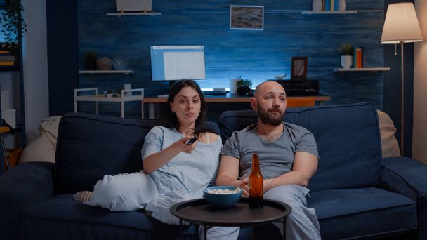 Couple spending evening dressed in pajamas arguing for remote control - Photo, Image