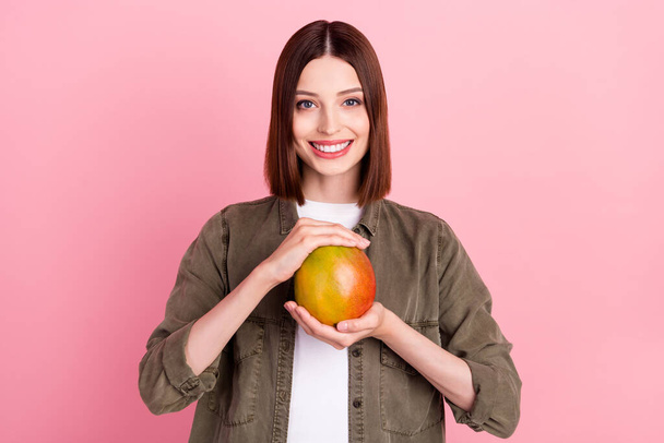 Photo of sweet brunette hairdo millennial lady hold mango wear green shirt isolated on pink color background - Foto, Imagen