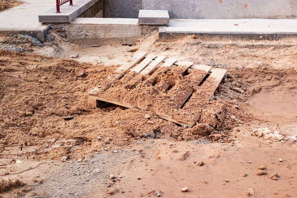 Eine Holzpalette im Boden und Schlamm liegen auf einer Baustelle - Foto, Bild