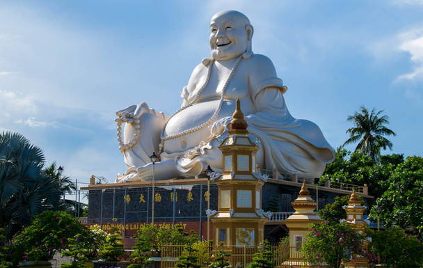 MY THO, VIETNAM - APRIL 25, 2018: Massive statue of the Sitting Smiling Buddha at the Vinh Tranh Pagoda in My Tho, the Mekong Delta - Φωτογραφία, εικόνα