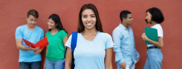 Beautiful mexican female student with group of multiethnic students outdoors in summer - Фото, изображение