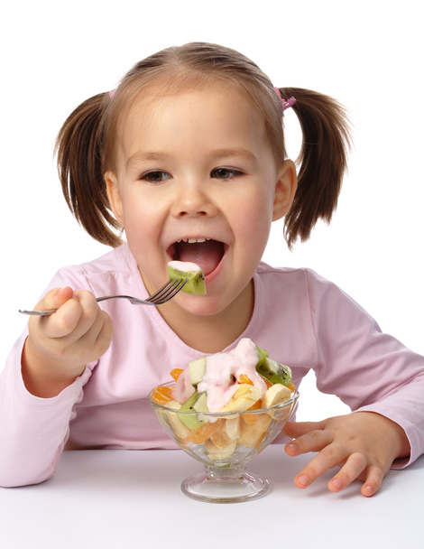 Little girl eats fruit salad - 写真・画像