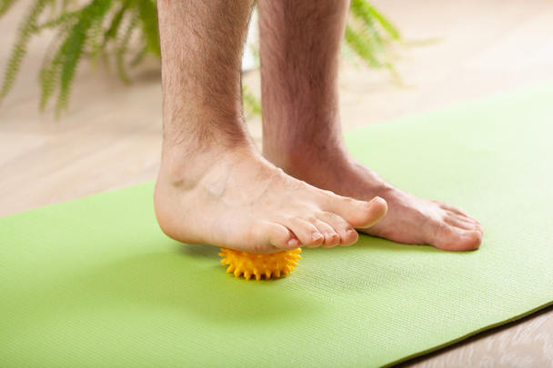 man doing flatfoot correction gymnastic exercise using massage ball at home - Zdjęcie, obraz
