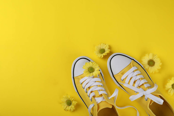 Gele sneakers met bloemen op gele achtergrond - Foto, afbeelding