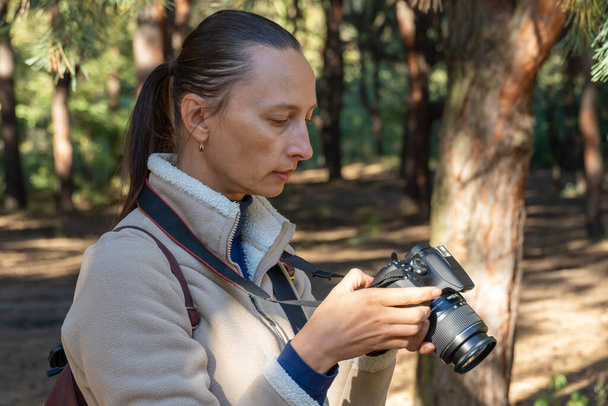 女性写真家が歩き、カメラで森林景観の写真を撮る。撮影自然. - 写真・画像