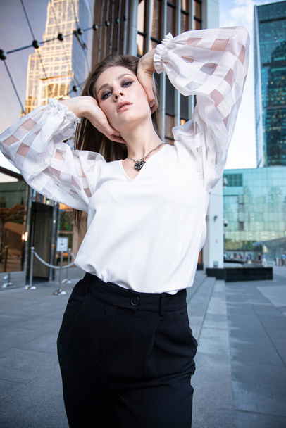 Jonge zakenvrouw op straat van een moderne stad in een witte blouse - Foto, afbeelding