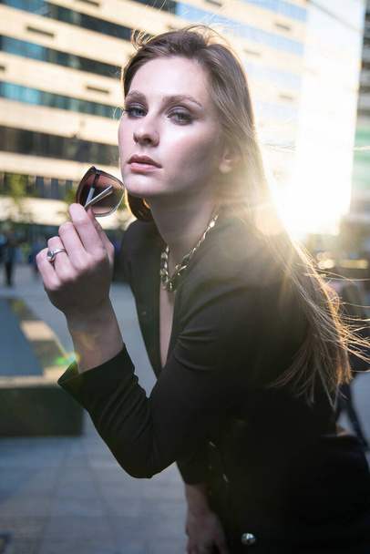 Young business woman on the street of a modern city with glasses in her hand - Foto, Bild
