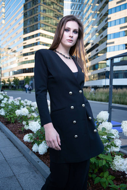 Young business woman in modern city of skyscapers with flower bed behind - Φωτογραφία, εικόνα