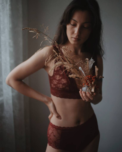 beautiful woman in red underwear with dry flowers - Photo, Image