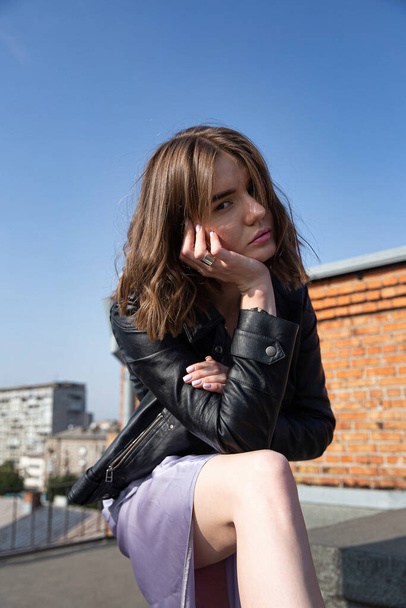 Young european woman sitting on the roof with city view behind - Foto, Imagem