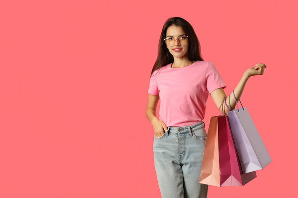 Chica atractiva con bolsas de papel multicolores sobre fondo rosa. - Foto, imagen