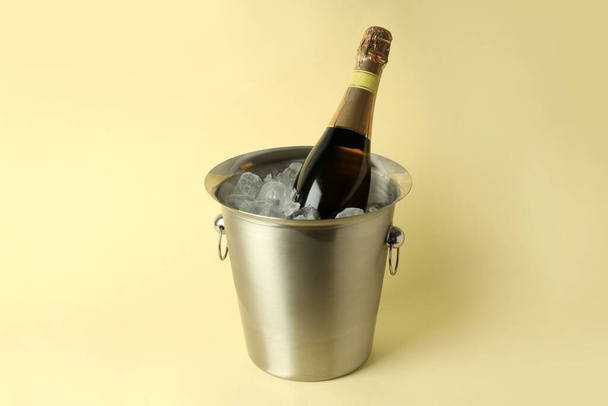 Secchio in metallo con ghiaccio e bottiglia di Champagne su sfondo beige. - Foto, immagini