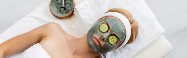 top view of woman with clay mask and cucumber slices on eyes lying on massage table, banner - Foto, immagini