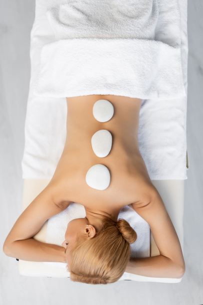 Draufsicht auf hübsche Frau, die Hot-Stone-Massage im Wellness-Center erhält  - Foto, Bild