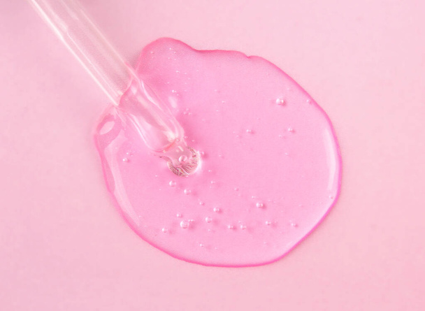 Піпетка з рідкою гіалуроновою кислотою на рожевому фоні. Концепція косметики та охорони здоров'я крупним планом
 - Фото, зображення