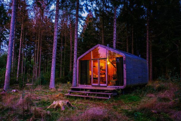 Holzhütte im Herbstwald in den Niederlanden, Hütte ohne Gitter, Holzhütte umgeben von bunten gelben und roten Herbstbäumen - Foto, Bild