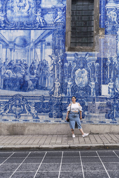 A vertical panoramic shot of a caucasian girl posing in front of a blue artistic wall - Foto, Bild