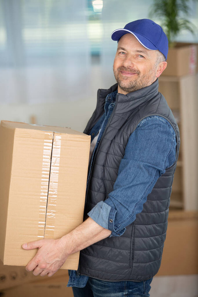 smiling friendly delivery man carrying parce - Foto, Bild