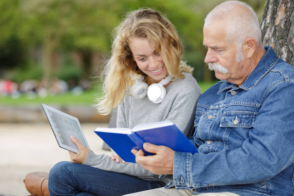 senior man and woman reading a book in park - Foto, imagen