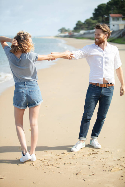 couple on the beach with interlinked arms - Zdjęcie, obraz