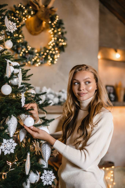 young beautiful woman model with long hair in a beige suit christmas tree christmas In brown wooden - Foto, afbeelding
