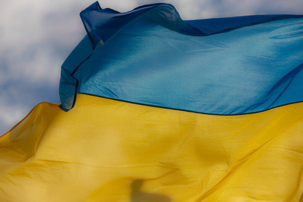 Флаг Украины, размахивающий на ветру против голубого неба
. - Фото, изображение