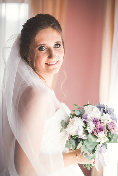 Gorgeous bride in robe posing and preparing for the wedding ceremony face in a room - Foto, imagen