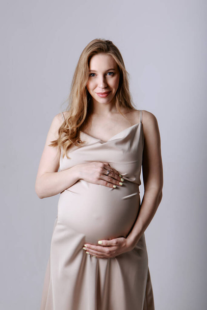 caucasian pregnant woman stroking her belly on white background. Copy space. The concept of healthy digestion, lifestyle, IVF - Foto, afbeelding