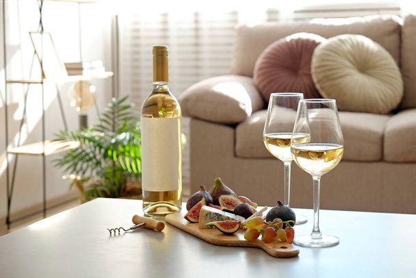 Bottle of a vintage chardonnay with two poured glasses, figs, grapes, blue cheese and grissini breadsticks. Copy space, top view, flat lay, close up, background. - Fotoğraf, Görsel