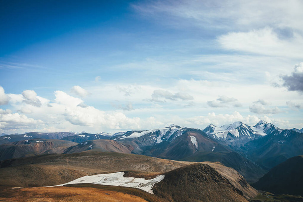 Barevná alpská scenérie s krásným malým ledovcem ve vysoké horské poušti mezi kopci a zasněženými horami ve slunečním světle pod modrou oblohou s cirrusovými mraky. Scénická slunná krajina horské pouště. - Fotografie, Obrázek
