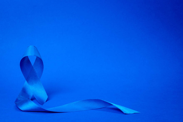 Cinta de próstata azul. Conocimiento de la salud de los hombres en noviembre con cinta de cáncer de próstata azul aislado en fondo azul profundo. Noviembre y Día Internacional del Hombre - Foto, imagen