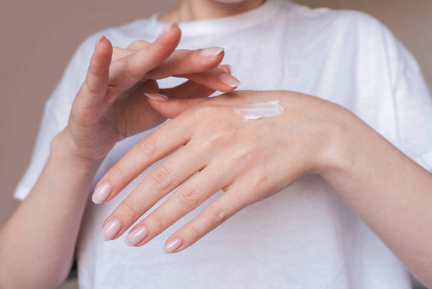 Mãos femininas aplicando creme hidratante. Conceito de cuidado corporal - Foto, Imagem