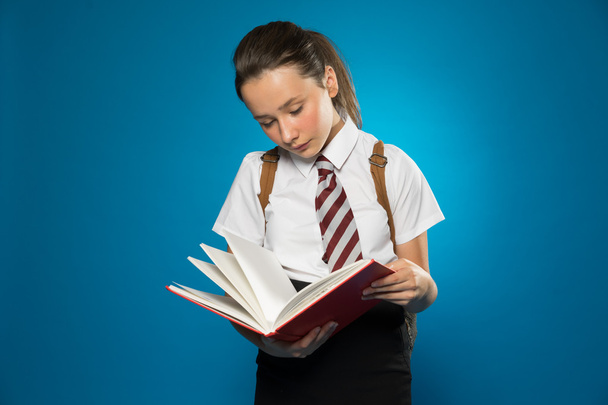 Young schoolgirl reading from a class text book - Foto, imagen