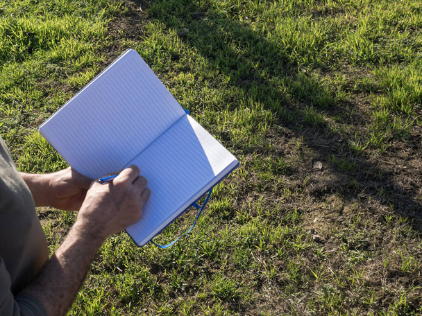 Mature farmer taking notes in a notebook in the field. Agricultural concept. - Φωτογραφία, εικόνα