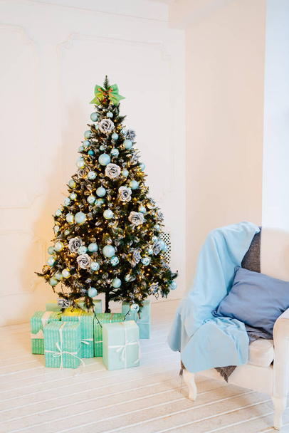 chair with blue pillow and blanket against near christmas tree with garland - Valokuva, kuva