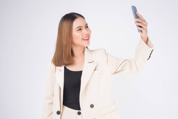 Portrait of young beautiful woman in suit using smart phone over white background	 - Фото, зображення