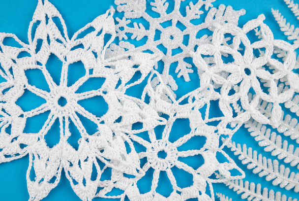 Winter theme white crochet snowflakes on light blue background. Above view, studio shot. - Фото, зображення