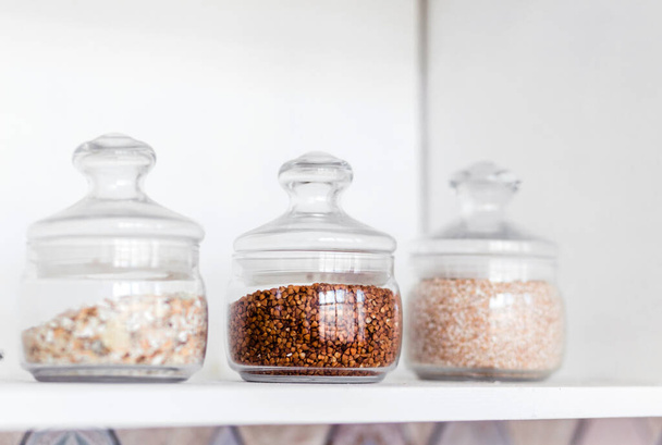 Vasi di vetro di cereali sono sullo scaffale in cucina. Foto - Foto, immagini