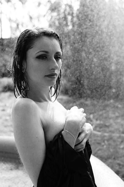 Όμορφη υγρή γυμνή γυναίκα σε σκούρο πουκάμισο ποζάρουν στην πισίνα εξωτερική, μαύρο και άσπρο  - Φωτογραφία, εικόνα