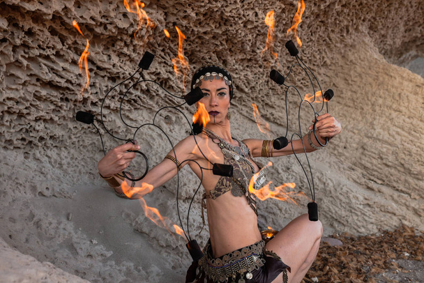 Cabo de Gata, Almeria, Hiszpania. Kobieta występująca z fankami ognia na plaży ćwicząca swój występ. - Zdjęcie, obraz