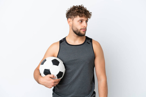 Νεαρός όμορφος καυκάσιος άνδρας απομονωμένος σε λευκό φόντο με μπάλα ποδοσφαίρου - Φωτογραφία, εικόνα