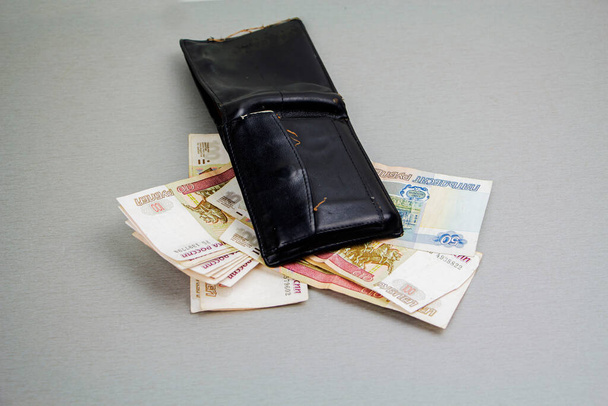 Ρετρό-μαύρο πορτοφόλι και χαρτονομίσματα των 1000 και 100 ρουβλίων που προεξέχουν από αυτό. Επιχειρήσεις και χρηματοοικονομικά, η έννοια του πλούτου. Κρίση - Φωτογραφία, εικόνα