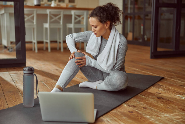 Slim woman hurting knee during online training - Photo, Image