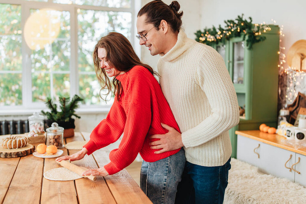 Young happy couple backing cooking at christmas winter holidays on the kitchen indoors ate home light image - Foto, imagen