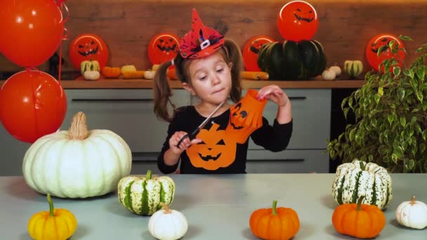 Una ragazza con emozioni sta tagliando lanterne di carta in preparazione per Halloween. - Filmati, video