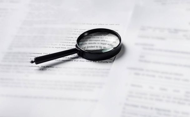 Magnifying glass lying over heap of paper documents. Investigation and financial audit concept - Foto, Bild