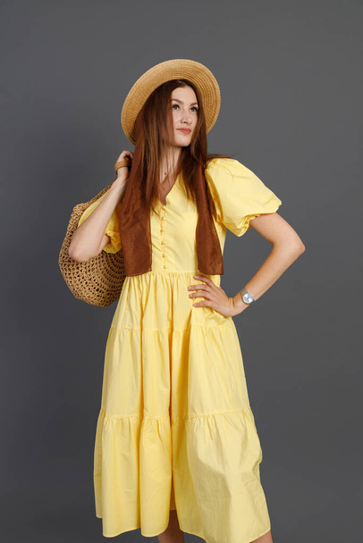 Charming woman in yellow dress standing in studio - Zdjęcie, obraz