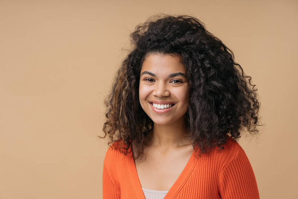 Studio portrait of beautiful smiling African American woman looking at camera isolated on background. Young stylish teenager with curly hair, white teeth posing for pictures. Natural beauty   - Foto, afbeelding